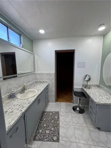 a spacious bedroom with a bed a mirror on dresser and a wooden floor