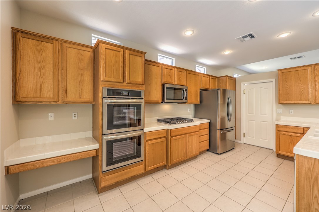 3713 Spring Shadow Road Las Vegas, NV 89129 - Photo 15 of 37 A well-appointed kitchen features warm wooden cabinetry, integrated appliances, and a convenient built-in desk area.