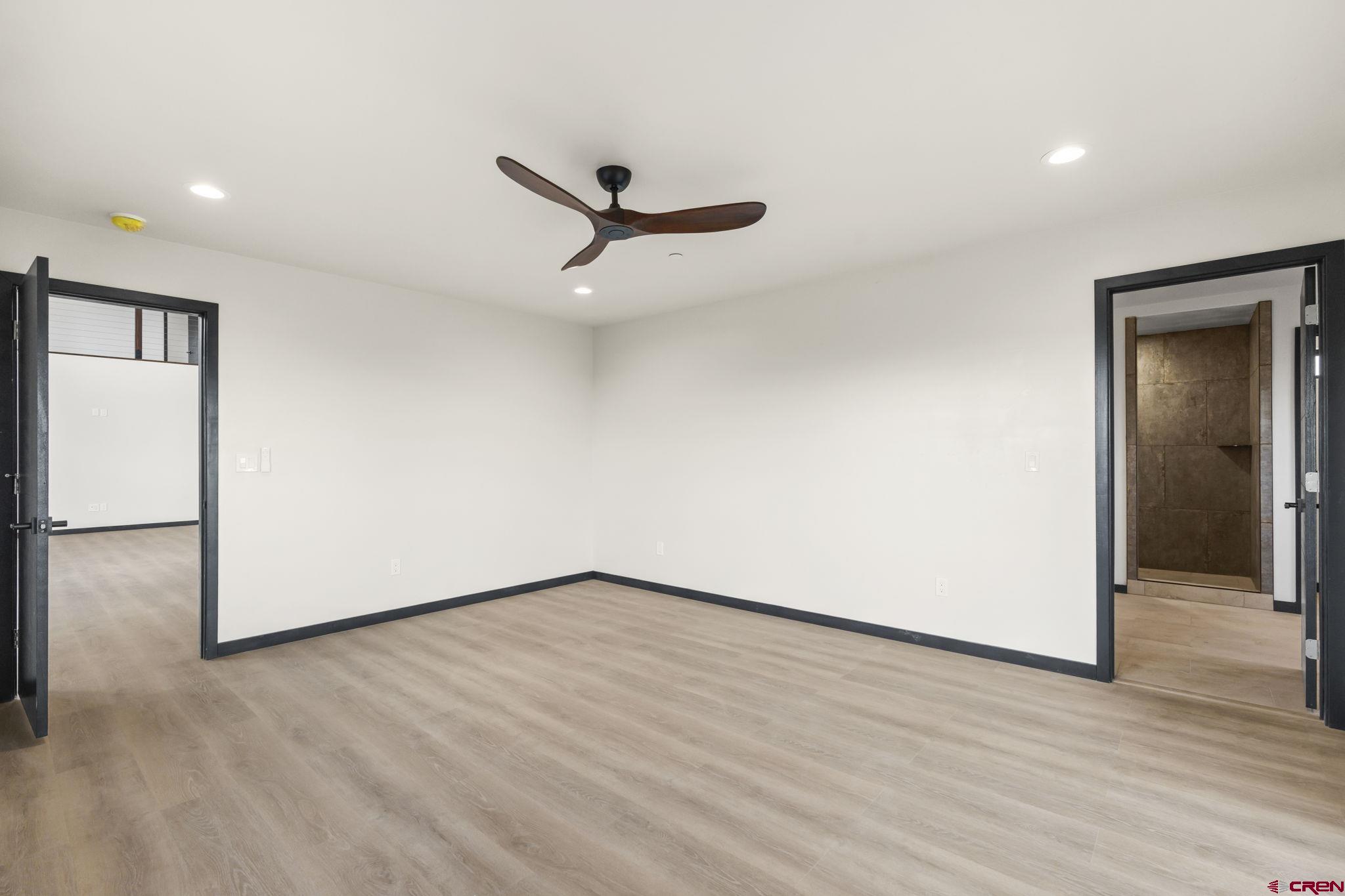 192 Rawhide Road Durango, CO 81303 - Photo 13 of 41 an empty room with wooden floor a ceiling fan and windows