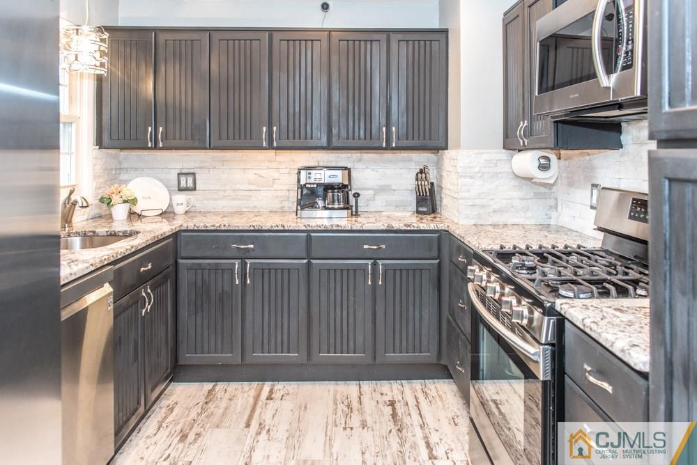 29 Mercer Road Old Bridge, NJ 08857 - Photo 7 of 24 a kitchen with stainless steel appliances granite countertop a stove a sink and a microwave