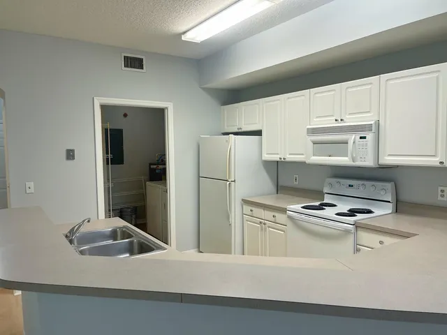 a kitchen with stainless steel appliances granite countertop white cabinets and refrigerator