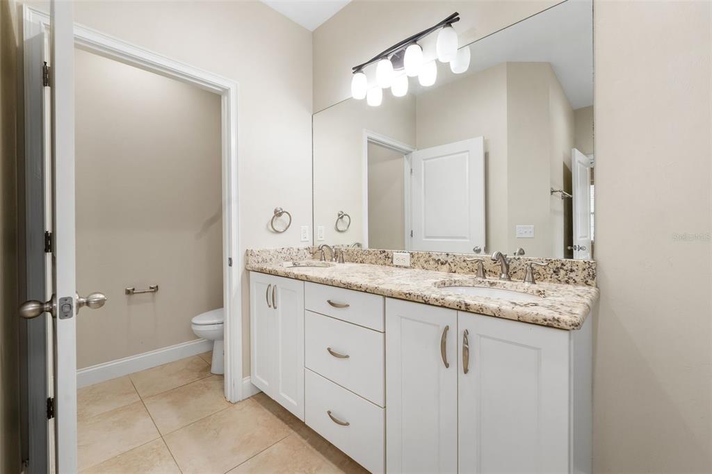 16617 Northwest 194th Street High Springs, FL 32643 - Photo 21 of 32 a bathroom with a granite countertop sink a toilet and a mirror