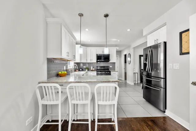 a kitchen with stainless steel appliances granite countertop a refrigerator a stove a sink dishwasher a oven with a dining table and chairs