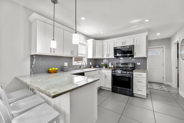 a kitchen with stainless steel appliances granite countertop a sink a stove a microwave and a refrigerator