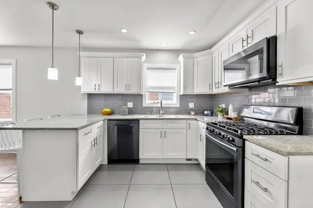 a kitchen with stainless steel appliances granite countertop a sink a stove a microwave and wooden cabinets