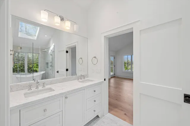 a bathroom with a sink double vanity granite tub shower and a mirror
