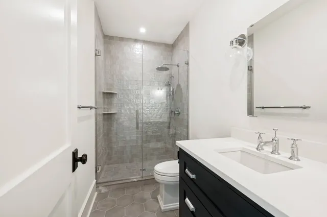 a bathroom with a granite countertop sink toilet a mirror and shower