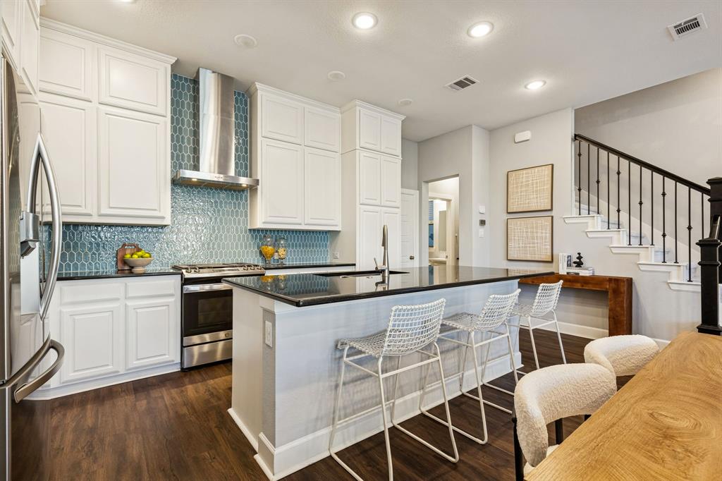 7119 Amber Grove Dallas, TX 75231 - Photo 11 of 30 a kitchen with stainless steel appliances granite countertop a stove a sink and white cabinets with wooden floor