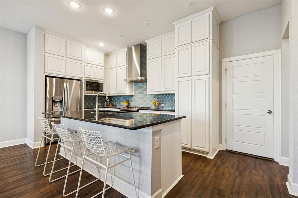 7119 Amber Grove Dallas, TX 75231 - Photo 9 of 30 a kitchen with stainless steel appliances granite countertop a stove a refrigerator and a refrigerator with wooden floor