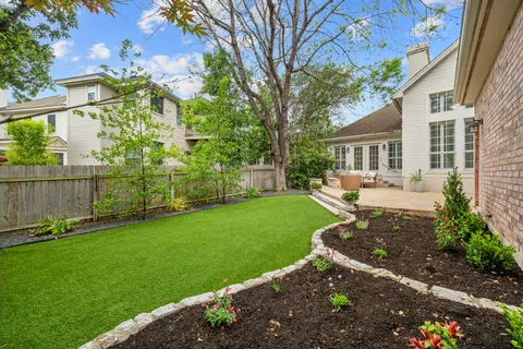 a view of a yard with plants and large tree