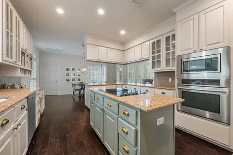 a kitchen with kitchen island granite countertop a sink stove and cabinets