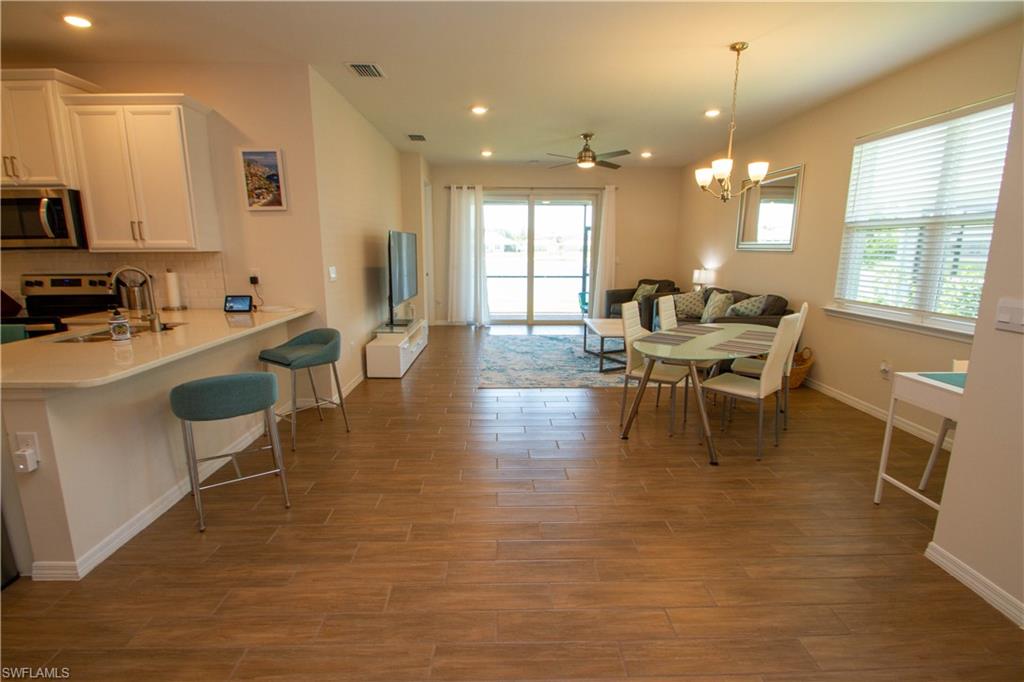 1241 Enbrook Loop Naples, FL 34114 - Photo 19 of 50 a dining room with stainless steel appliances a table chairs refrigerator and sink
