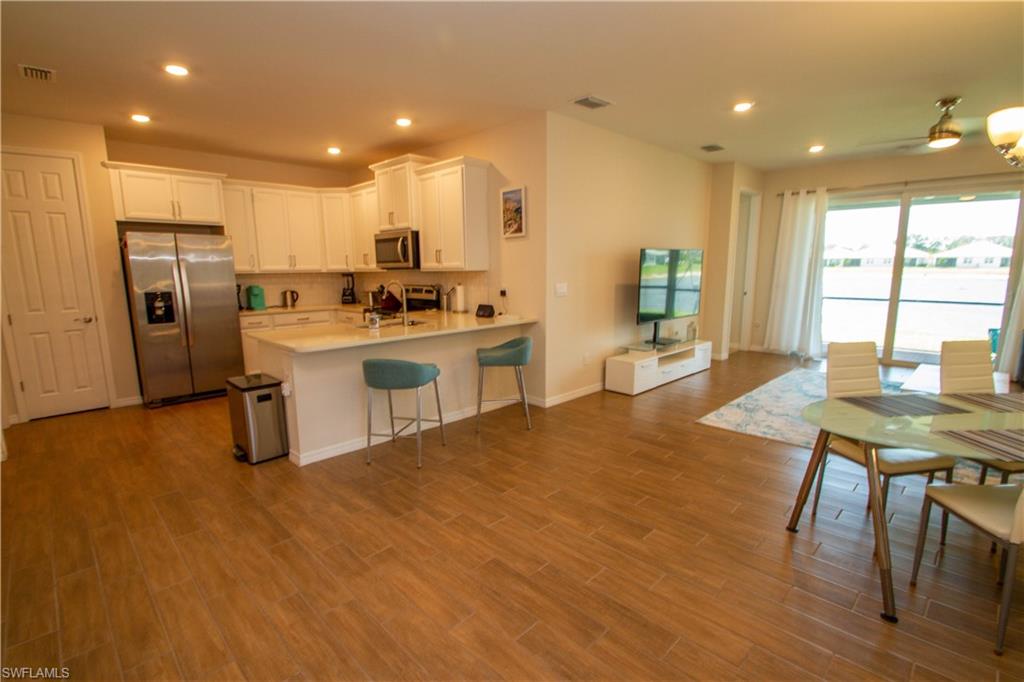 1241 Enbrook Loop Naples, FL 34114 - Photo 3 of 50 a kitchen with stainless steel appliances a stove a refrigerator a sink dishwasher with a dining table and chairs