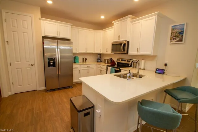 a kitchen with stainless steel appliances a sink a stove a refrigerator cabinets and a dining table