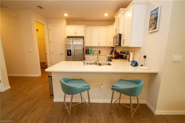 a kitchen with stainless steel appliances a dining table chairs and a refrigerator