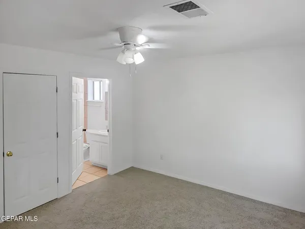 an empty room with a chandelier fan and windows