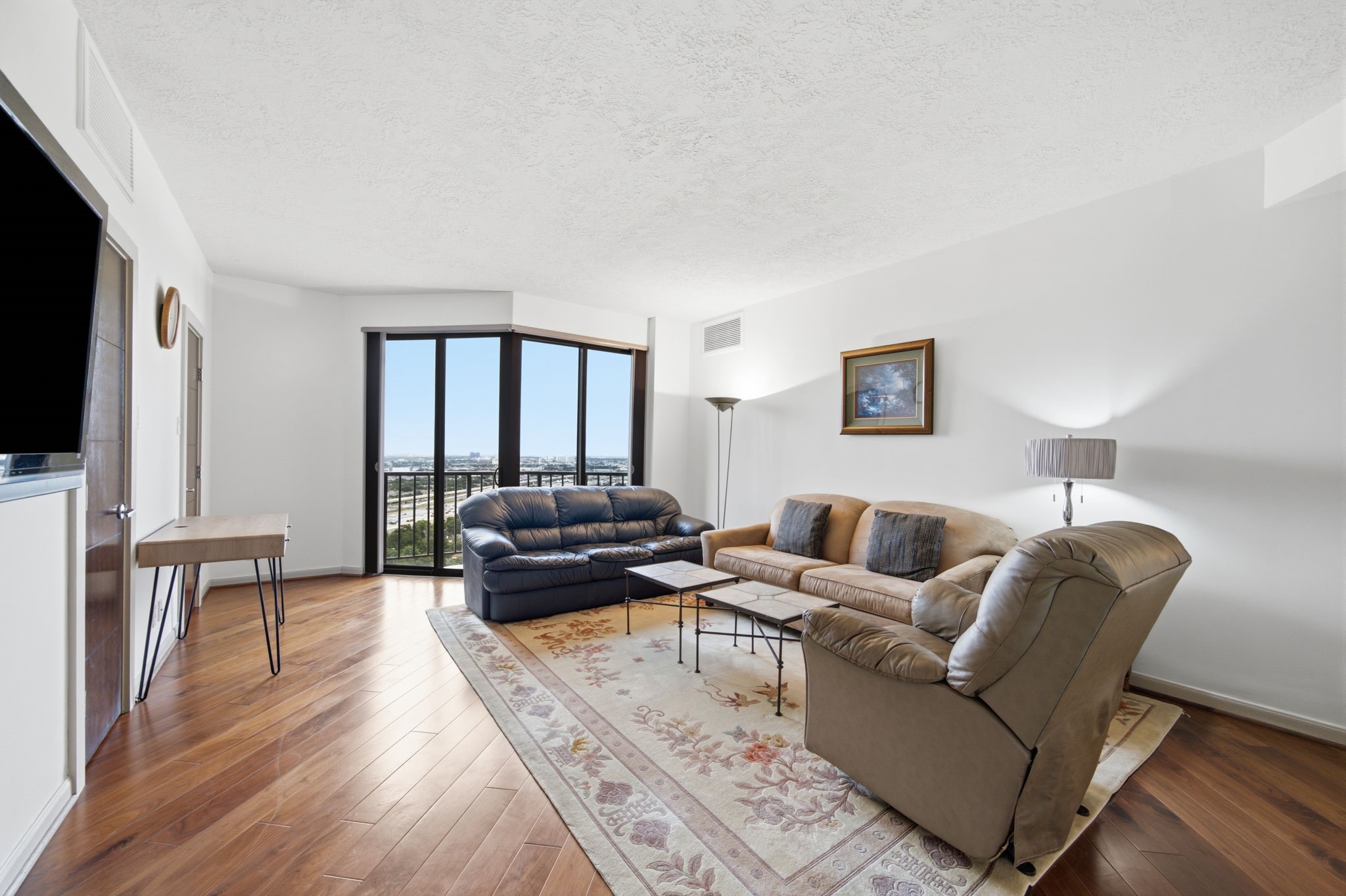3350 McCue Road, Unit 2402 Houston, TX 77056 - Photo 35 of 49 Gleaming hardwood floors extend across this versatile secondary living space, accented by clean lines and generous wall space for a mounted media center. Expansive floor-to-ceiling glass doors open directly to a private balcony, framing panoramic city horizon views.