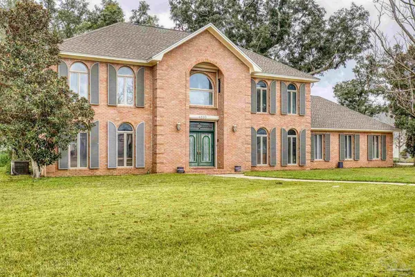 a view of a yard in front of a brick house with a large windows