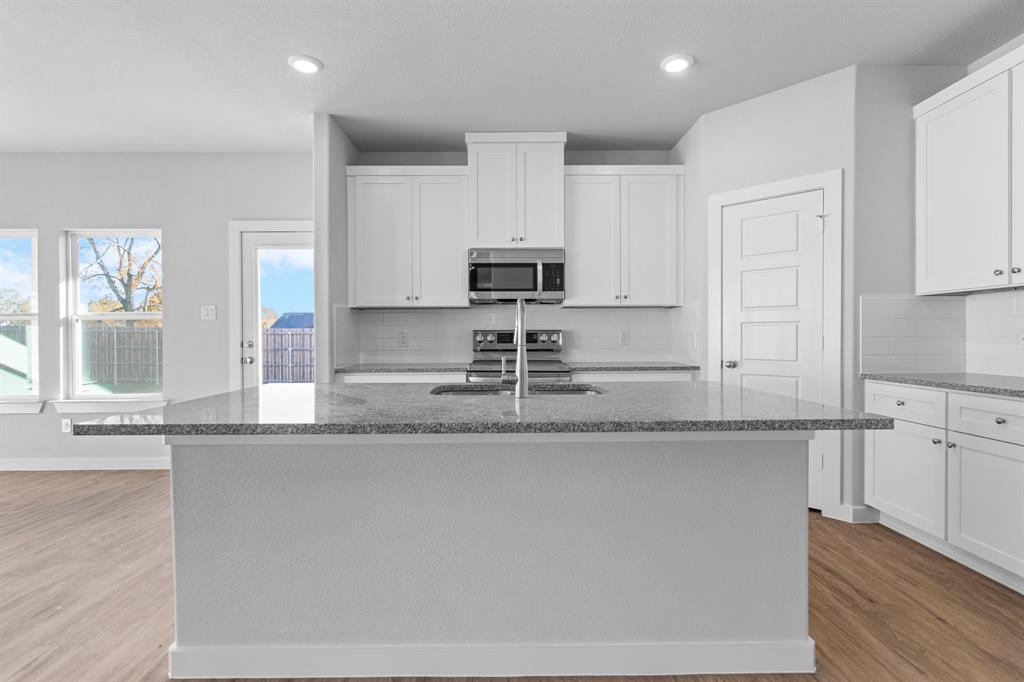 227 Faith Lane Tioga, TX 76271 - Photo 10 of 26 a kitchen with granite countertop a sink and a stove top oven