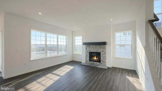 an empty room with wooden floor fireplace and windows