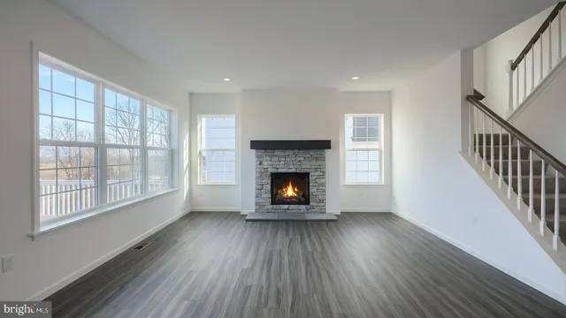 a view of an empty room with wooden floor fireplace and a window