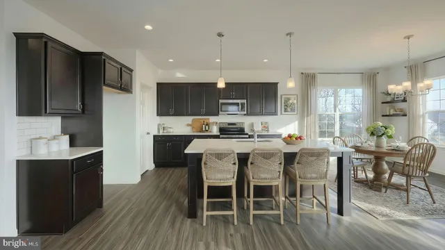 a kitchen with stainless steel appliances granite countertop a stove a refrigerator a sink a dining table and chairs with wooden floor