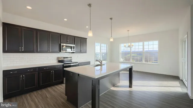 a kitchen with stainless steel appliances granite countertop wooden cabinets a stove a sink and dishwasher with wooden floor