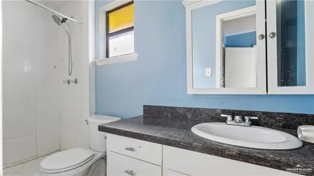 a bathroom with a granite countertop sink a toilet a mirror and shower