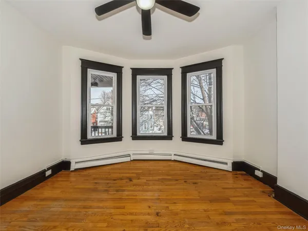 a view of an empty room with window and dresser