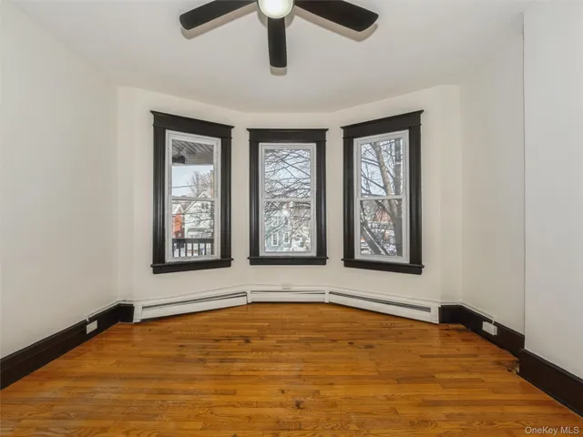 a view of an empty room with window and dresser