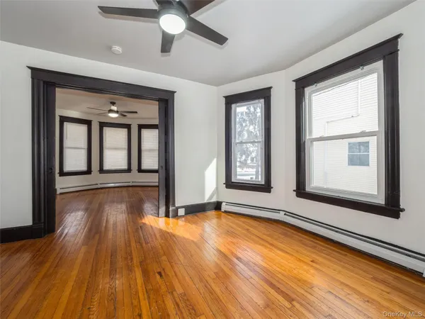 a view of an empty room with wooden floor and a window