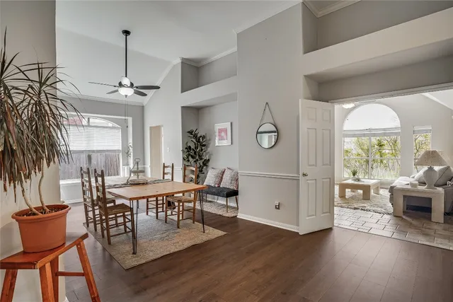 a dining room with wooden floor a chandelier a glass table and chairs