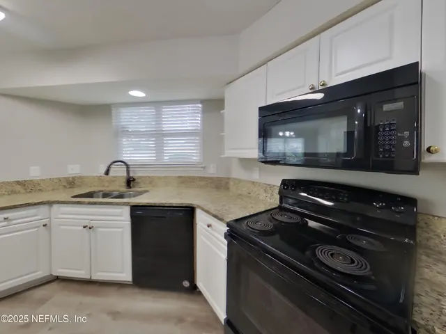 a kitchen with granite countertop a sink a stove and cabinets