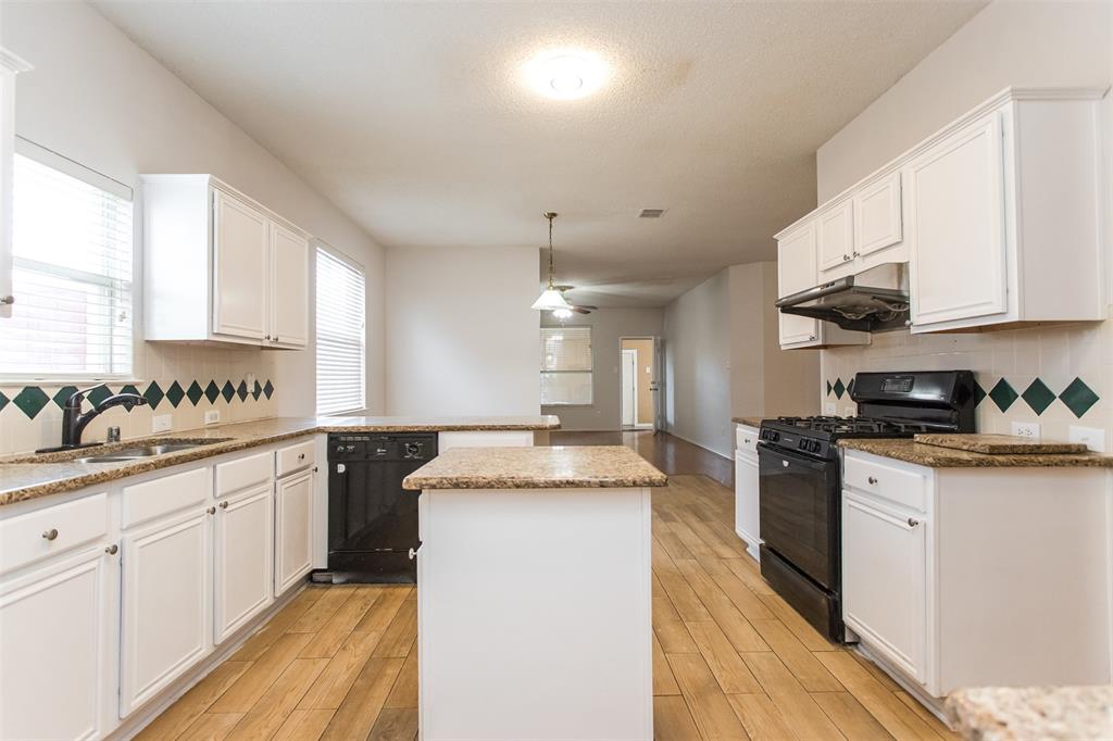 738 Opal Lane Mesquite, TX 75149 - Photo 12 of 31 Kitchen with decorative backsplash, a kitchen island, black appliances, white cabinets, and under cabinet range hood