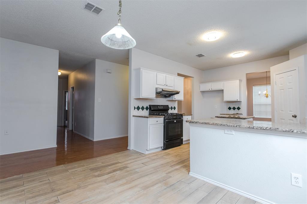738 Opal Lane Mesquite, TX 75149 - Photo 14 of 31 Kitchen featuring hanging light fixtures, white cabinetry, light stone countertops, black gas range, and a textured ceiling