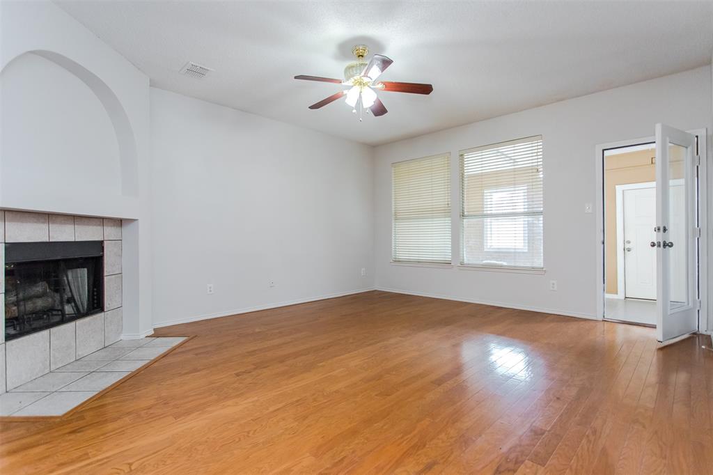 738 Opal Lane Mesquite, TX 75149 - Photo 6 of 31 Unfurnished living room with light wood-style flooring, a tiled fireplace, and ceiling fan