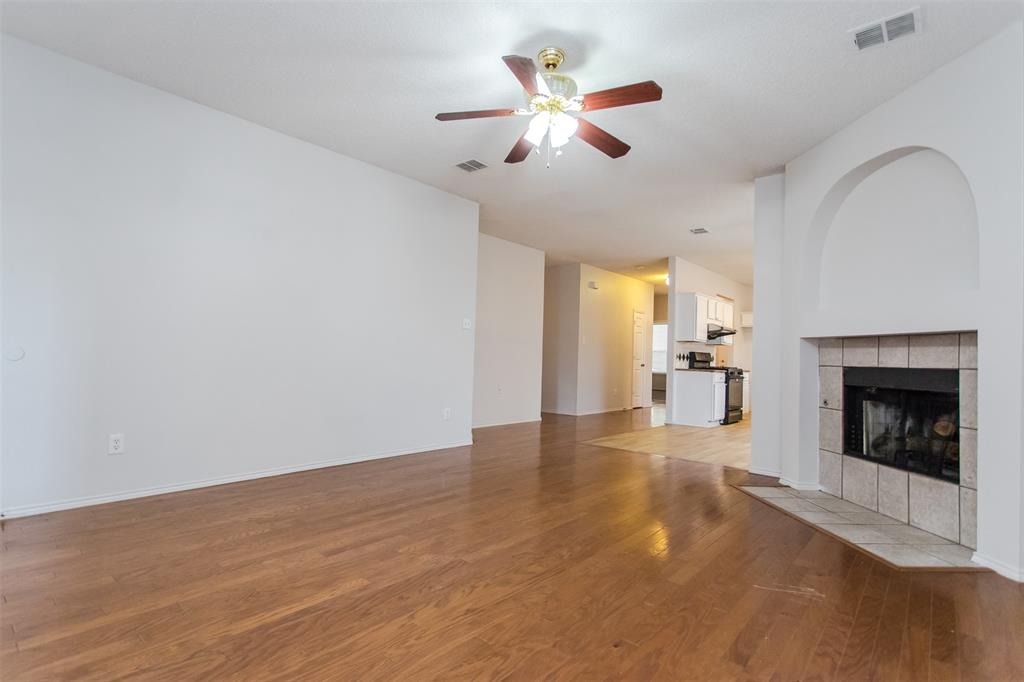 738 Opal Lane Mesquite, TX 75149 - Photo 7 of 31 Unfurnished living room featuring light wood-style flooring, a tile fireplace, and a ceiling fan