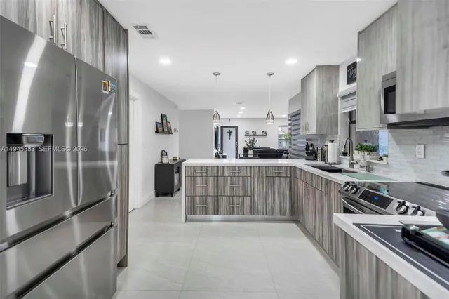 a kitchen with stainless steel appliances granite countertop a refrigerator a sink and white cabinets