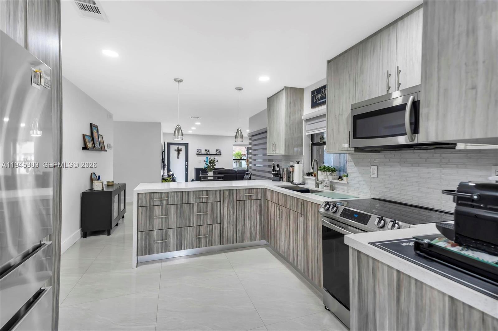 12736 Southwest 68th Lane Miami, FL 33183 - Photo 16 of 37 a kitchen with stainless steel appliances a stove sink microwave and cabinets
