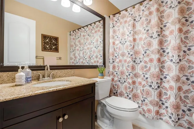 a bathroom with a granite countertop sink and a toilet