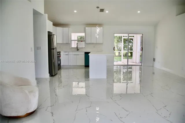 a kitchen with stainless steel appliances kitchen island granite top and refrigerator