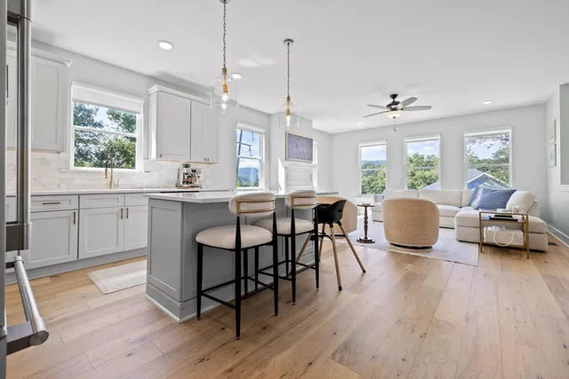 a kitchen with stainless steel appliances a dining table chairs refrigerator and microwave