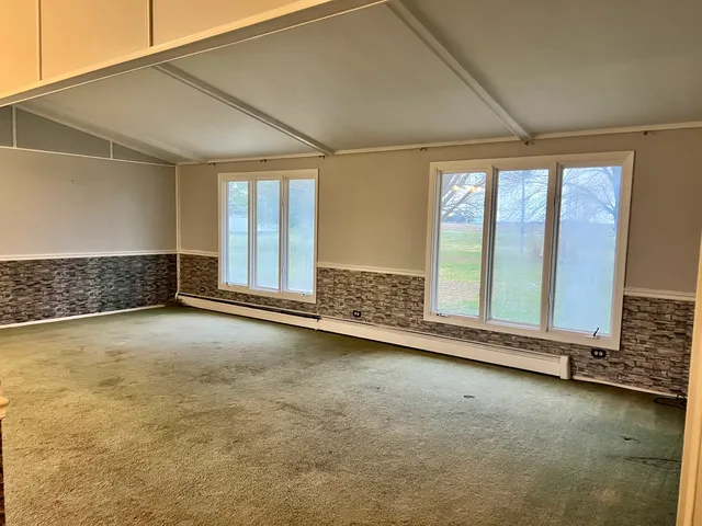 an empty room with a fireplace and large window