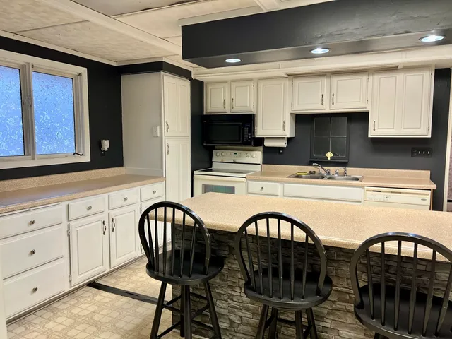 a kitchen with stainless steel appliances granite countertop a table chairs sink and cabinets