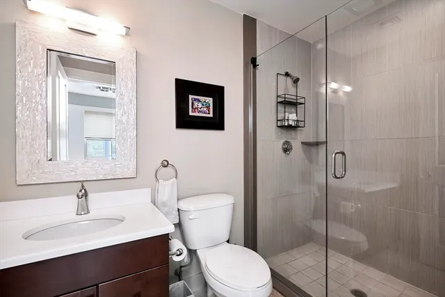 a bathroom with a toilet sink vanity granite and shower