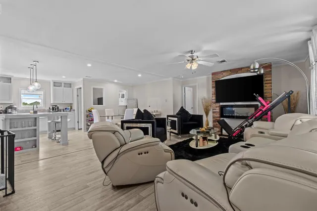 a living room with furniture a flat screen tv and kitchen view