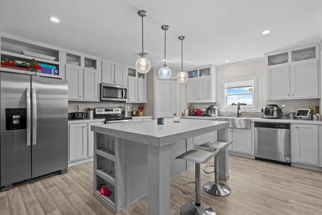 a kitchen with kitchen island granite countertop a sink a counter space stainless steel appliances and cabinets