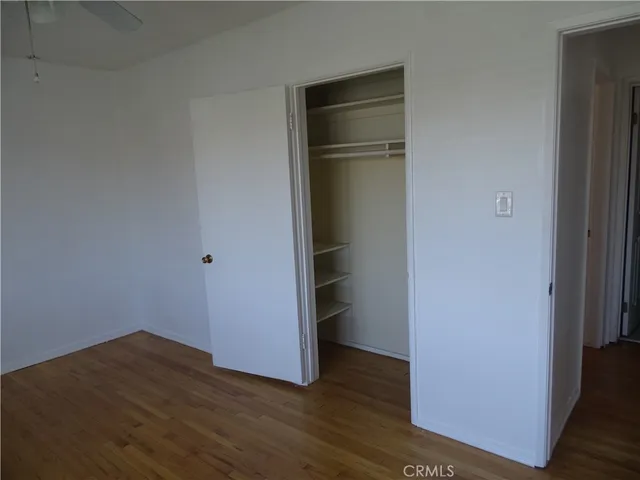 a view of an empty room with wooden floor and closet