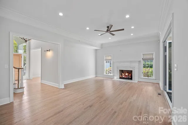 an empty room with wooden floor fireplace and windows
