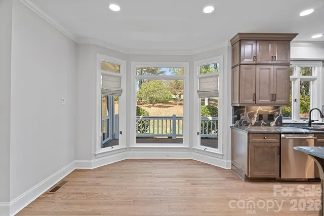 a view of a kitchen with an empty room and wooden floor